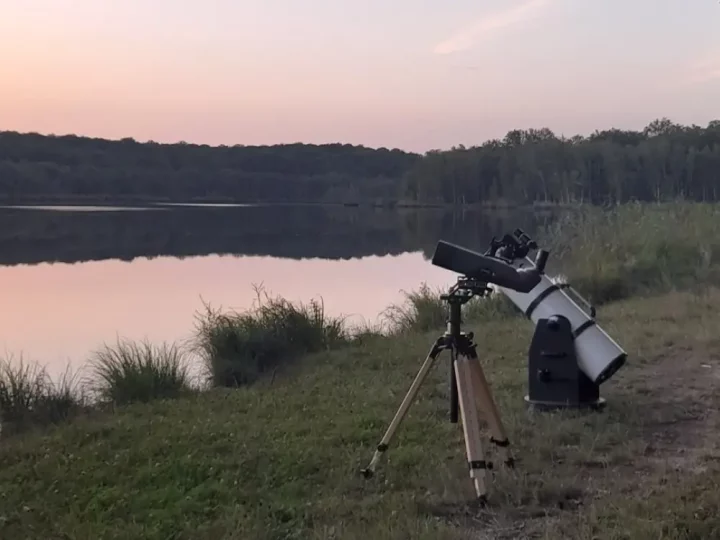Télescope au bord d'un étang à la tombée de la nuit
